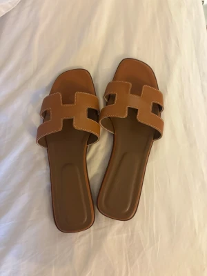 Bruna slip-in sandaler - Superfina oanvända bruna slip-in sandaler med fyrkantig tå och bred rem i läderlook🌸 Mycket små i storleken, passar 37-38 (men står 40) se bild. Var tyvärr för smala och långa för mig med en extra bred och kort fot💗Köpta på Vinted för 699kr 