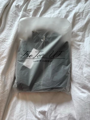 Mörkblå stickad cardigan med dragkedja (Pris diskuterbart) - Snygg mörkblå stickad cardigan från TreTon UF med hög krage och dragkedja framtill. Tröjan har ribbad struktur och ser riktigt varm och skön ut, perfekt för kyliga dagar. Enkel och stilren design som passar till det mesta.