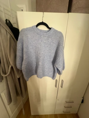 Ljusblå stickad tröja Gina Tricot - Mysig ljusblå stickad tröja från Gina Tricot med oversized passform och rund hals. Tröjan har ribbade muddar vid hals, ärmslut och nederkant. Perfekt för lager på lager och chill vardagsstil.