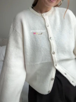 Krämvit kofta från Gina Tricot - Mysig vit kofta från Gina Tricot med rund halsringning och knappar framtill. Koftan har en rak och något boxig passform med långa ärmar och ribbade detaljer vid hals och knappslå. Perfekt att slänga på sig när det är kyligt. Storlek XS. Ny med prislapp