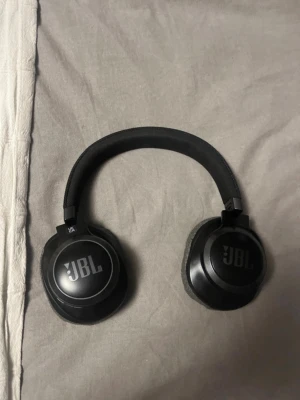 Jbl over-ear hörlurar - Stilrena over-ear hörlurar i grått tygmaterial med svart insida och vadderad bygel. Perfekta för att lyssna på musik eller poddar med bra komfort och snygg design.ANC Funkar ej