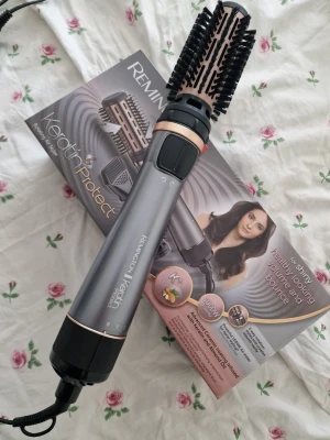 Remington Keratin Protect varmluftsborste - Remington Keratin Protect varmluftsborste i grå och svart med roséguld detaljer. Borsten har roterande funktion och flera värmelägen. Perfekt för att skapa volym och glans i håret. Levereras med originalkartong. Endast testad. 