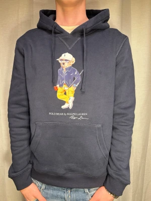 Blå Ralph Lauren Hoodie - Säljer en mörkblå polo Ralph lauren hoodie. Storleken som står är L (men sitter mer som en M) Modellen på bilden är ca 183 o väger ca 70 kg. Skriv vid minsta fundering.