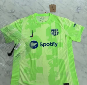 Barcelona Nike fotbollströja S - Barcelona fotbollströja från Nike i neonljus grön med mönstrade blockdetaljer. Tryck med Spotify och UNHCR-logga, samt klubbmärke på bröstet. Kortärmad modell i lätt och ventilerande polyester, perfekt för match eller träning. Priset kan diskuteras