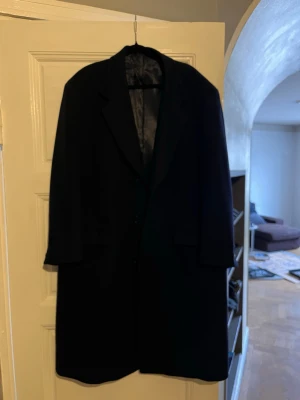 Svart ullrock från Piacenza - Klassisk svart ullrock från Piacenza med elegant snitt och slät finish. Rocken har breda slag, knäppning framtill och helfodrad insida med exklusiv känsla. Perfekt för dig som vill ha en stilren och tidlös look. Vintage köpt i Paris, använd 1 gång 80ull20kashmir