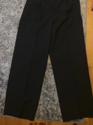 Ken pants, weekday - Säljer ett par svarta kostymbyxor från weekday. Byxorna har klassisk pressveck och stängs med dold knapp och dragkedja. Perfekta för en stilren och trendig look.