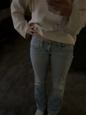 Ljusblå raka Pepe jeans från London. Lågmidjade och bootcut. - Säljer ett par ljusblå jeans med rak passform och klassisk femficksdesign. Jeansen har normal midja och är lågmidjade och bootcut och tvåknappig.