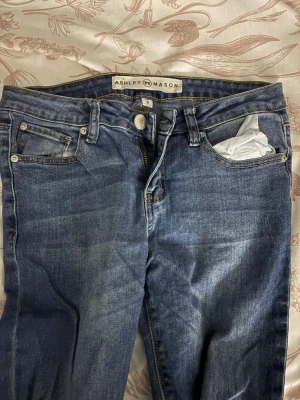 Blå jeans från Ashley Mason - Snygga blå jeans från Ashley Mason med klassisk femficksdesign. Jeansen har en normal passform och är tillverkade i mjuk bomull med lite stretch för extra komfort. De har kål i knäna.