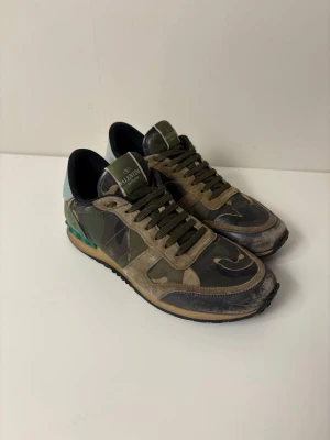 Valentino rockrunner camo - Säljer dessa snygga valentino rockrunner skor! Skorna har den snygga camo färgen! Skicket är bra med täcken på användning!
