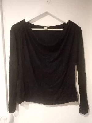 Svart långärmad topp från H&M - En svart långärmad topp från H&M med lös passform och rundad halsringning. Toppen är enkel och stilren, perfekt att matcha med olika outfits. Tillverkad i ett mjukt och stretchigt material för extra komfort.