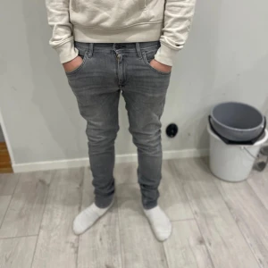 Replay grå jeans Wallys  - Säljer ett par grå jeans från Replay, modell Wallys. Jeansen har snygga slitningar. Materialet är mjukt jeans-tyg och färgen är en cool, lite tvättad grå ton. Perfekt för dig som gillar stilrena och moderna jeans.