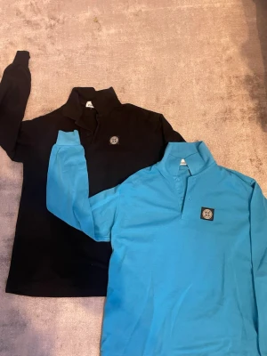 Stone Island långärmad henley - Två långärmade henley-skjortor från Stone Island, en i svart och en i klarblå. Båda har klassisk krage, knappslå och den ikoniska Stone Island-loggan på bröstet. Perfekta för en clean och avslappnad stil. Mitt pris: 600kr för båda två. Storlek: L 