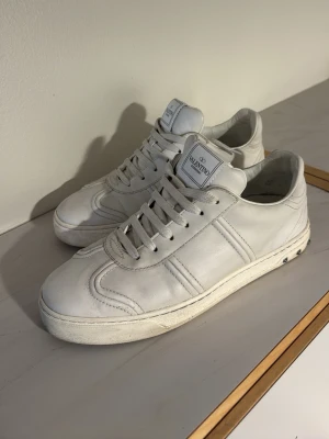 Vita sneakers från Valentino - Stilrena vita sneakers från Valentino i lågt modellutförande. Skorna är tillverkade i slätt läder med matchande vita skosnören och diskret logga på plösen. Klassisk design med ton-i-ton detaljer och bekväm sula. Ingen sko låda till, en spik är borta 