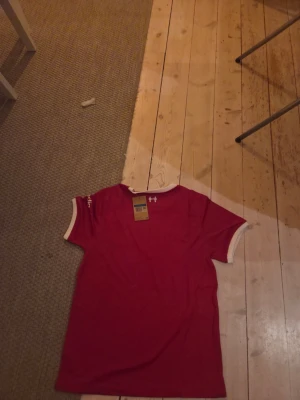 Liverpool matchtröja Nike röd - Snygg röd Liverpool matchtröja från Nike med vita detaljer vid ärmslut och krage. Tröjan har klubbmärke, Nike-logga och sponsortryck på bröstet. Perfekt för dig som vill stötta laget på match eller träning.