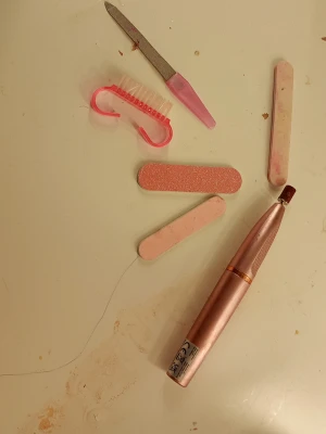 Nagelvårdsset med rosa filar och elfil - Nagelvårdsset med flera rosa nagelfilar, buffertblock, nagelborste och en elektrisk nagelfil i metallicrosa. Perfekt för att fila, forma och polera naglarna hemma. Innehåller både klassiska filar och en smidig elfil för snabbare resultat.