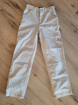 Beige cargobyxor med raka ben - Snygga beige cargobyxor med raka ben och flera praktiska fickor på sidorna och bak. Byxorna har bälteshällor och stängs med knapp och dragkedja. Perfekta för en avslappnad och trendig stil.