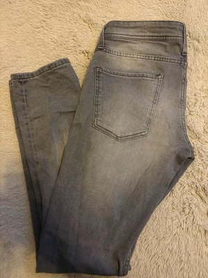 Gråa slim fit jeans - Snygga gråa slim fit jeans med klassisk femficksdesign och diskret tvättad look. Jeansen har normal midja och raka ben, perfekta till en avslappnad stil. Materialet känns mjukt och följsamt, vilket gör dem bekväma att bära hela dagen.