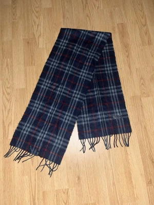 Rutig halsduk från Burberrys i ull - Varm burberry halsduk  100%äkta burberry  Färg- blå med nyanser av röd  Storlek- No size   Pris går att diskuteras vid snabb affär!      Skickar inom 24h📦🚚  Har du någon fråga är det bara att fråga på!  