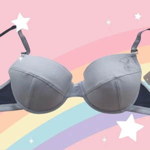 Ljusblå bh 75B med Snoopy-detalj - Supersöt ljusblå bh med uttagbara inlägg och en liten Snoopy-figur på ena kupan. Axelbanden är glittriga och både justerbara och avtagbara för bästa flexibilitet. Detta var den mest klassiska behån i början av 2000-talet och har räddats från ett restlager. Orginalapparna är kvar. Se även mina andra anonnser, du får 20% bundlerabatt om du köper flera.