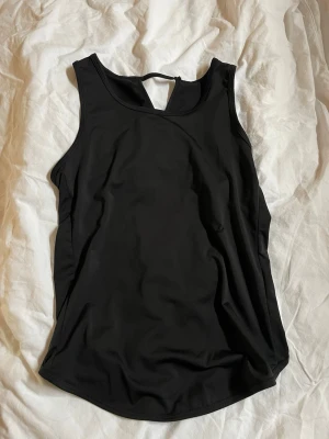 Svart omlott linnetopp - Snygg svart linnetopp med omlottdetalj i ryggen och rundad halsringning. Linnet är i träningsmaterial.