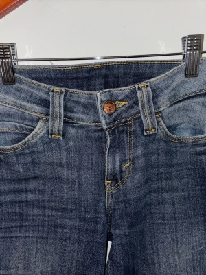 Blå jeans från Cheap monday  - Säljer ett par blå jeans från weekday/cheap monday. Jeansen har kontrastsömmar i gult och en grön etikett med logga bak. De är i storlek 26/30. 