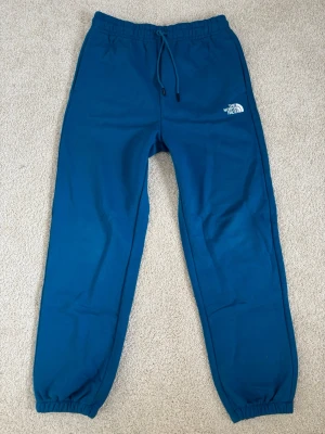 Blå mjukisbyxor från The North Face - Snygga blå mjukisbyxor från The North Face med resår i midjan. De är i storlek unisex M och jättemjuka inuti. Byxorna är knappt använda så de är som nya.