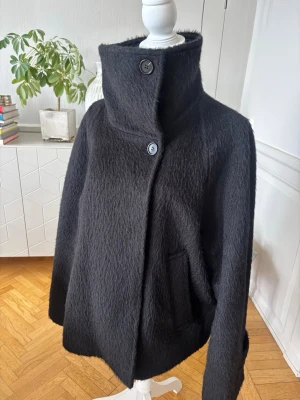 Svart ullkappa med hög krage - Säljer den trendiga Arket jackan! Storlek 42 (för ville ha den lite oversized) men jag har S/M på sista bilden. Ordinarie pris 2290kr! 🩷