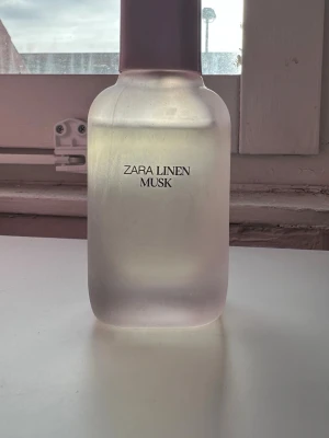Zara Linen Musk parfym - Zara Linen Musk parfym i en stilren, frostad glasflaska med rundade former och vit kork. Doften är fräsch och mjuk med inslag av mysk och linne, perfekt för dig som gillar subtila och eleganta parfymer.