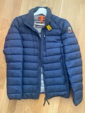 Mörkblå dunjacka Parajumpers XS - Snygg mörkblå dunjacka från Parajumpers i storlek XS. Jackan har fin design . Parajumper Märkespatch på armen och innerfoder i grått. Bra för  våren där du har på dig kläder dom är lätt att bära.