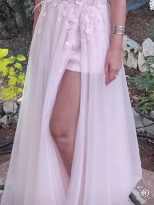 Balklänning  - En superläcker klänning i tyll.  Överdelen är full av blommor, pärlor och små stenar.  Använd en gång på ett bröllop och fick så mycket fina komplimanger.   Under tyllen är det glittriga skjorts med knappar nertill ifall man behöver gå på toaletten under festen.  Slits på ena benet.  Vadderad byst 133 cm Midja ca 76 runt Armhåla till armhålan 40 Den är  tvättad Passar storlek 36-40 Min längd med klackskor 174 Klänningens längd från byst ner till golvet  Köpt i en fin butik utomlands för 3000kr