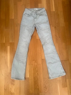 Ljusblå bootcut jeans - Snygga ljusblå jeans med bootcut passform och klassisk femficksdesign. Jeansen har hög midja och dragkedja med knapp framtill. Perfekta för dig som gillar en retroinspirerad look och vill ha ett par jeans som sticker ut lite extra.