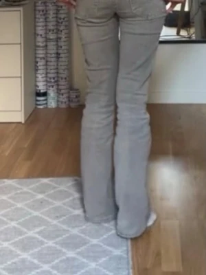 Grå bootcut jeans - Säljer ett par gråa bootcut jeans med klassisk femficksmodell och normal midja. Jeansen har en snygg tvättad look och är tillverkade i ett mjukt denimtyg som sitter bekvämt. Perfekta för dig som gillar en avslappnad men trendig stil.