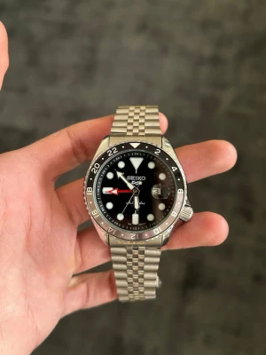 SEIKO 5 SPORTS GMT MOD - Helt ny SEIKO 5 SPORTS GMT med Automatisk Seiko-NH35-urverk. ✅  Öppen baksida (display caseback).✅  Storlek: 40mm✅ rostfritt stål, reptåligt safirglas, svart urtavla med datum, GMT-funktion gör det möjligt att visa två olika tidszoner samtidigt ✅  Medföljer klocklåda, ej original✅  Vid fler frågor eller funderingar skicka gärna ett pm, Mvh