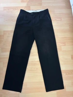 Weekday Kostymbyxor  - Svarta kostymbyxor från weekday i modell Conrad Wide Trousers. Använda men inga defekter som påverkar helhetsintrycket. Riktigt snygga byxor som tyvärr har blivit för små för mig. Snygg modell med vida ben och pressveck