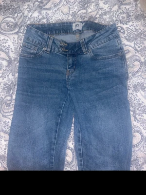 Blå jeans XS från 157 - Säljer ett par klassiska blå jeans från 157 i storlek XS med full längd. Jeansen har fem fickor, bälteshällor och stängs med knapp och dragkedja. Perfekta till vardags och passar till det mesta. Materialet är denim i bomull.