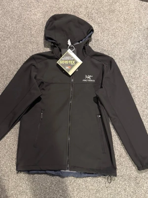 Svart Arc'teryx vindjacka med huva - Snygg svart vindjacka från Arc'teryx med GORE-TEX-material.. dragkedja sönder.