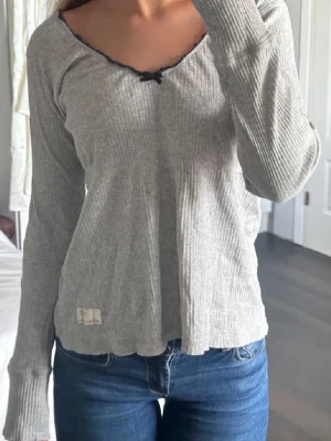 Grå ribbad långärmad topp - Säljer min älskade grå oddmolly tröja.💓Som har en fågel på armen och rosett vid halsen. 💘💘passar storlekarna S-L🫶🏼 Skriv för fler bilder så löser jag det! Lägger upp igen för fri frakt