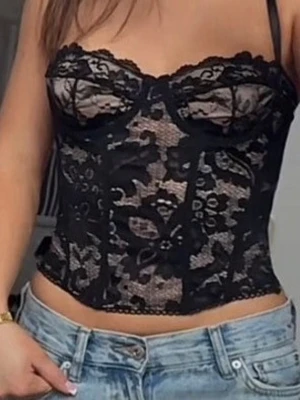 Svart spetskorsett med blommönster - Säljer en snygg svart korsett i genomskinlig spets med blommönster och tunna axelband. Modellen har bygel under bysten för extra stöd och en figurnära passform. Perfekt för dig som vill ha en trendig och feminin look.