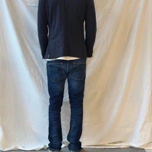 Mörkblå Nudie Jeans Grim Tim - Storlek: W34 L36. Modell: Grim Tim. Mått:                Midja tvärs över: 43 cm / Ytterbenslängd: 108 cm / Innerbenslängd: 82 cm 