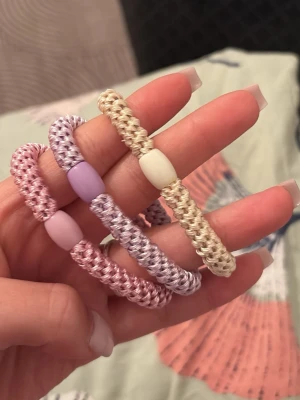 Pastellfärgade spiralhårsnoddar - Tre spiralformade hårsnoddar i pastellfärger: rosa, lila och beige. Varje snodd har en matchande plastdetalj i mitten. Perfekta för att skapa en söt och trendig look. Tillverkade i elastiskt material med glansig finish.