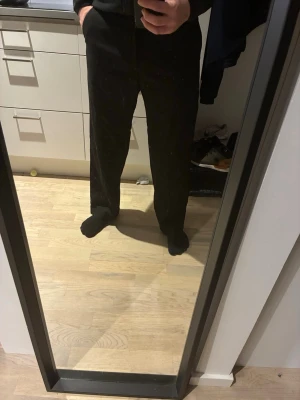 Svarta kostymbyxor med rak passform - Säljer ett par klassiska svarta kostymbyxor från Bershka med vid passform. Byxorna har diskreta fickor i sidorna och är tillverkade i ett tunt, mjukt tyg som ger en clean look. Perfekta till skjorta eller stickad tröja. Knappt använda.