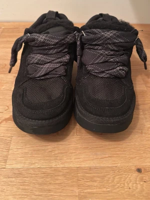 Svarta sneakers från UGG -                           PRIS KAN DISKUTERAS Säljer ett par svarta sneakers från UGG med grova snören och meshdetaljer. Skorna har en robust sula och insida i mjukt material för extra komfort. Perfekta för dig som gillar en sportig och trendig look.