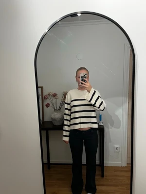 Vit stickad tröja med svarta ränder - Säljer en vit stickad tröja med breda svarta horisontella ränder. Tröjan har en avslappnad passform, är något croppad och har långa ärmar. Perfekt för en trendig och casual look.