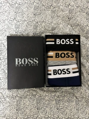 3-pack kalsonger  - Säljer ett 3-pack kalsonger i olika färger: svart, beige och marinblå med bred resår och BOSS-logga. Snygg design med kontrastfärgade ränder på midjebandet. Kommer i originalförpackning, perfekt för dig som gillar stilrena underkläder.