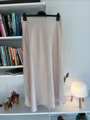 Beige långkjol i satin - Säljer denna jättefina ljusbeige/cremefärgade satinkjol från Kappahl då den inte kommer till användning så ofta som jag vill! Köpt för 399 på Kappahl. Mycket bra skick! Modellen rak och något klockad nedtill, och den är ankellång med stretchig resår i midjan (väldigt bekväm)🤗