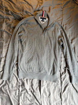 Grå 1/4 tröja Tommy Hilfiger - Snygg grå långärmad tröja från Tommy Hilfiger med halvzip. Den är storlek M men är lite mindre i passformen. Slim passform. Pris kan diskuteras.