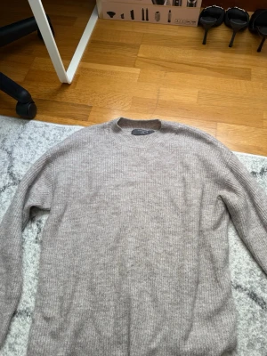 Beige stickad tröja med rund hals från primark - Mysig beige stickad tröja med rund hals och långa ärmar. Tröjan har en enkel, ribbad struktur och är perfekt för lager på lager. Passar dig som gillar en stilren och avslappnad look.
