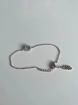 Lily & Rose, armband med ljusblå sten - Gulligt armband med blå sten i mitten, från märket Lily & Rose.  Används inte länge, så därför väljer jag istället att sälja det!