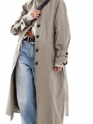 Beige trenchcoat med knappar - Stilren beige trenchcoat med svarta knappar och klassiska detaljer som bälte i midjan och justerbara ärmslut. Lång modell med avslappnad passform, perfekt för lager på lager. Tillverkad i ett lätt tyg som ger en snygg siluett.