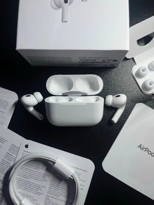 Apple AirPods Pro med laddningsetui - Säljer ett par vita Apple AirPods Pro med trådlöst laddningsetui. Hörlurarna har en stilren, kompakt design och levereras med utbytbara silikontoppar för perfekt passform. Perfekta för musik, samtal och brusreducering. Allt originaltillbehör och förpackning medföljer.